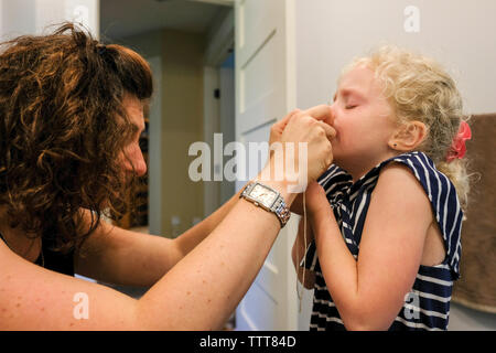 Vue de côté de mère dépose les dents de sa fille à la maison Banque D'Images