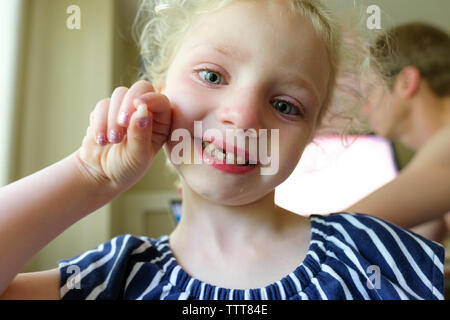 Close-up portrait of smiling girl montrant les dents primaires perdus en étant debout contre le père à la maison Banque D'Images