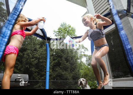 Soeurs de rire d'avoir de l'eau lutte sur trampoline en été Banque D'Images