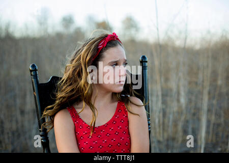 Upset girl looking away while sitting on chair Banque D'Images