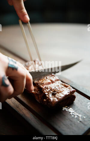 Portrait de mains de la viande rôtie sur la table de coupe Banque D'Images