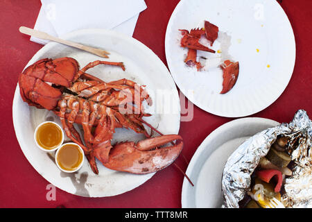 Vue supérieure de l'homard rôti et salade servi sur table rouge Banque D'Images