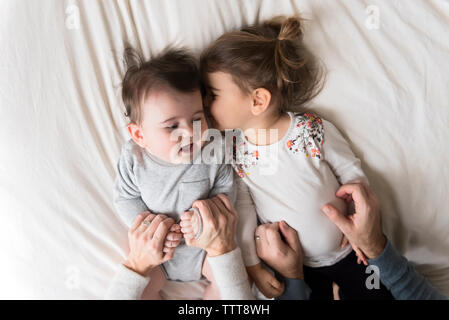 Les mains coupées des parents holding children sur le lit chez lui Banque D'Images