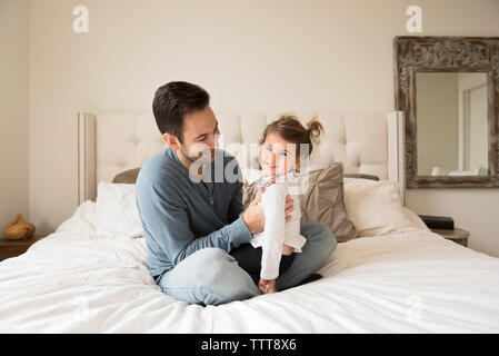 Portrait de fille joyeuse avec le père assis sur le lit à la maison Banque D'Images