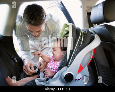 Bébé qui pleure en souriant père siège auto de verrouillage Banque D'Images