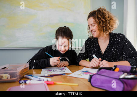 Mère Fille avec des dessins à colorier sur la table à la maison Banque D'Images