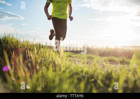 La section basse de l'homme exerçant sur terrain pendant le coucher du soleil Banque D'Images