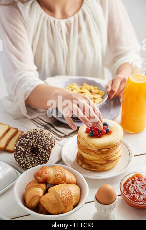 Midsection of woman having breakfast sur table tout en restant assis à la maison Banque D'Images