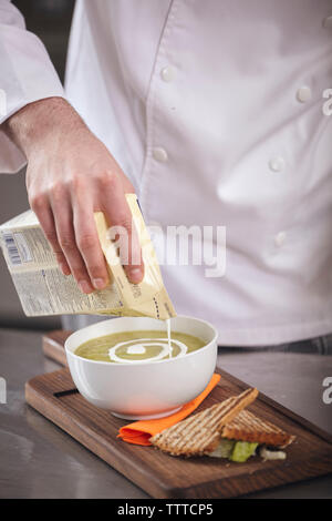 Portrait du chef pouring cream lors de la préparation de thé matcha par tranche de pain sur une planche à découper en cuisine commerciale Banque D'Images