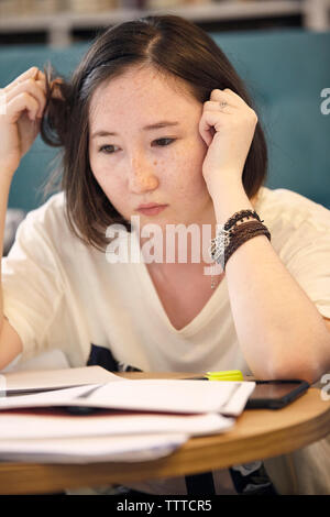 Close-up of young woman with books à loin à la maison Banque D'Images