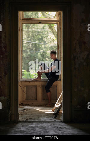 Vue latérale du ballet d'hommes sérieux à la recherche d'une fenêtre dans l'ancien bâtiment Banque D'Images