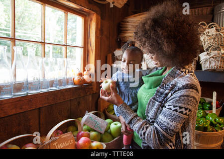 Mère montrant apple pour sa petite fille à organic shop Banque D'Images