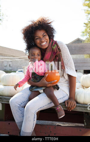 Happy mother holding pumpkin en position assise avec sa fille sur la table Banque D'Images