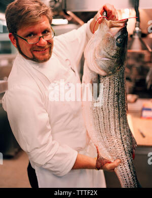 USA, Californie, Los Angeles, portrait de Chef Michael Cimarusti tenant un poisson dans la cuisine de son restaurant La Providence. Banque D'Images