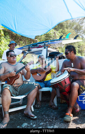 Polynésie française, Tahiti. Les surfeurs locaux à Papenoo Beach jouant des instruments. Banque D'Images