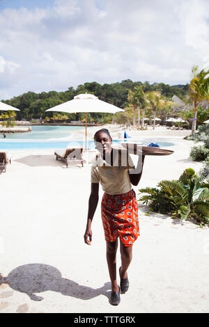 JAMAÏQUE, Oracabessa. GoldenEye Hotel and Resort. Personnel avec plateau de nourriture à la piscine. Banque D'Images