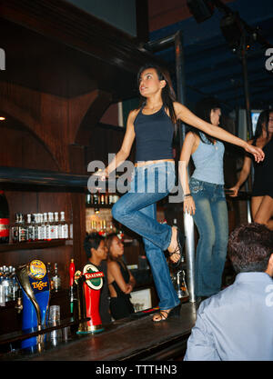 Singapour, les barmans danser dans la discothèque Bar CU. Banque D'Images