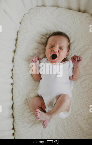 Vue aérienne de bâillements bébé fille couchée dans un lit bébé Banque D'Images