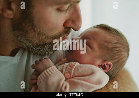 Close-up of father kissing baby girl at home Banque D'Images