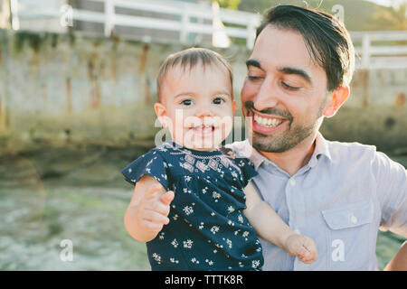 Portrait of baby girl menées par le père alors qu'il se tenait contre le mur Banque D'Images