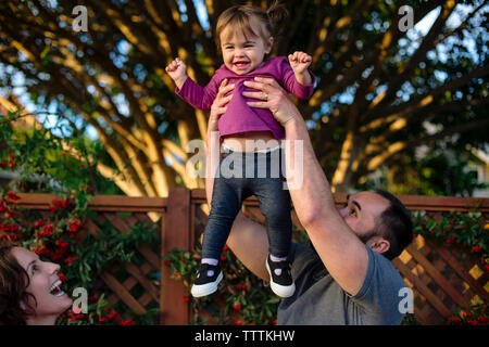 Heureux à la mère à fille joyeuse porté par père at park Banque D'Images