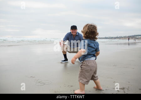 Père et fils jouant sur le rivage contre sky at beach Banque D'Images