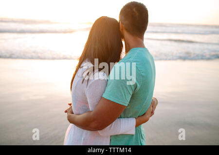 Couple en se tenant sur le rivage pendant le coucher du soleil Banque D'Images