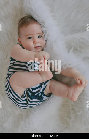 Passage portrait of cute baby boy lying on rug Banque D'Images