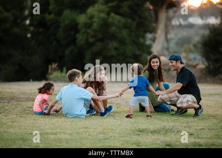 Cheerful family ring-autour-le-rosy at park Banque D'Images