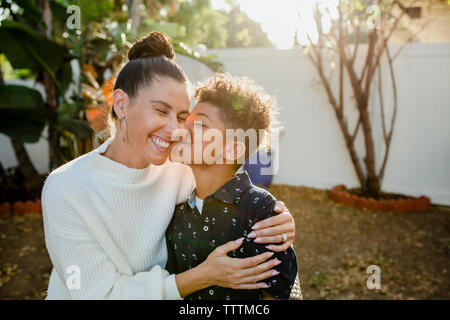 Fils aimant embrasser cheerful mère au jardin Banque D'Images