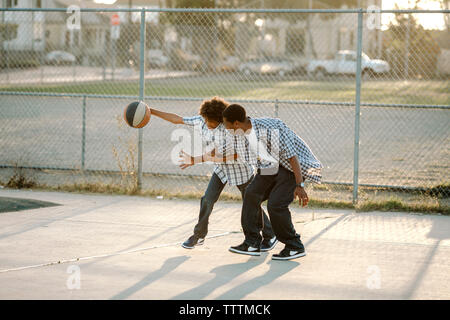 Toute la longueur d'un père et son fils jouer au basket-ball à la cour Banque D'Images
