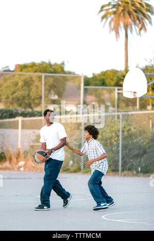 Père et fils jouer au basket-ball à l'aire de jeux Banque D'Images