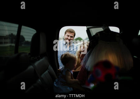 Smiling parents regardant baby girl in car Banque D'Images