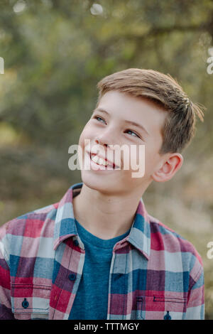 Close-up of thoughtful boy looking away while standing at park Banque D'Images