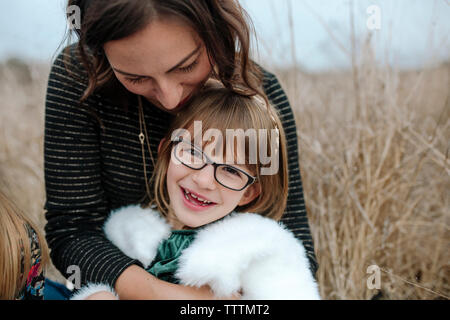 Close-up of mother with daughter sitting on grassy field Banque D'Images