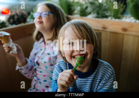 Portrait of happy brother eating ice cream avec sœur in cafe Banque D'Images