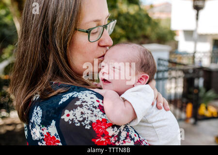 Close-up of mother kissing mignon fils nouveau-né sur balcon Banque D'Images