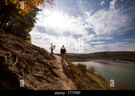 Homme backpackers marche sur route de terre contre ciel nuageux Banque D'Images