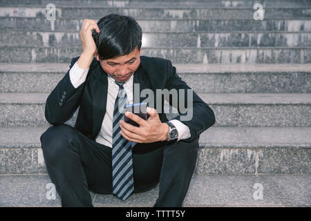 Les hommes d'Asie avec des maux de tête ou migraines à l'hôtel de ville après le travail des images de jeunes hommes d'affaires qui sont fatigués, stress, crise, dépression, failu Banque D'Images