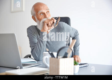 Happy man sitting with laptop in office Banque D'Images