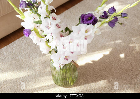 Belles fleurs dans vase en verre sur un tapis Banque D'Images