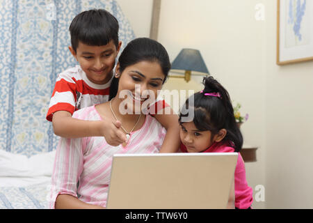 Femme avec ses enfants à travailler sur un ordinateur portable Banque D'Images