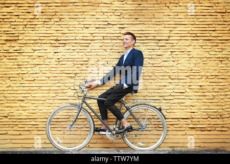 Jeune homme d'affaires avec Location sur mur de brique jaune background Banque D'Images