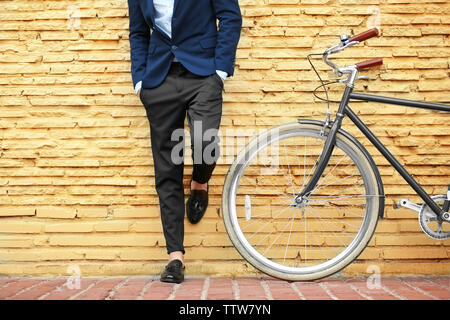 Jeune homme d'affaires avec Location sur mur de brique jaune background Banque D'Images