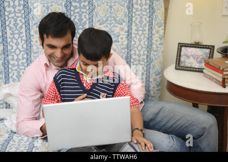 L'homme avec son fils travaillant sur un ordinateur portable Banque D'Images