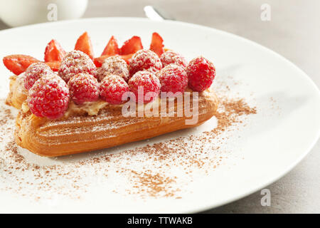 Éclairs délicieux aux fruits rouges, cannelle en poudre et le sucre on white plate Banque D'Images