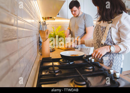 Couple cooking ensemble à la cuisine. faire frire les crêpes orange coupe de vie domestique. Banque D'Images