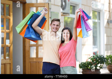 Couple heureux avec des sacs colorés dans la cour Banque D'Images