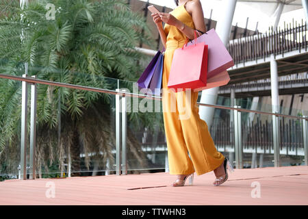 Femme à l'aide de smart phone holding shopping bags lifestyle mall dans le consumérisme. Banque D'Images