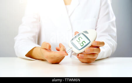 Photo de main du médecin avec glucomètre avec l'inscription 5 en studio sur fond gris Banque D'Images